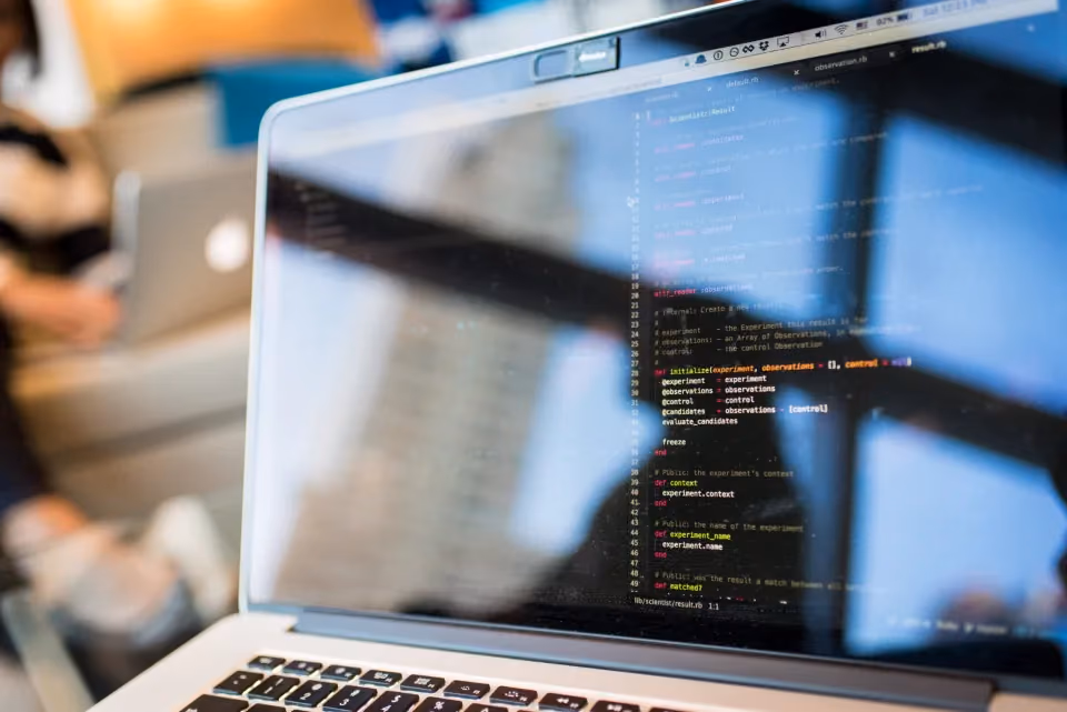 Ordinateur portable ouvert sur un écran de code, en contre-jour